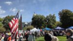 A view of an American flag and numerous protestors in front of the Colorado Capitol.